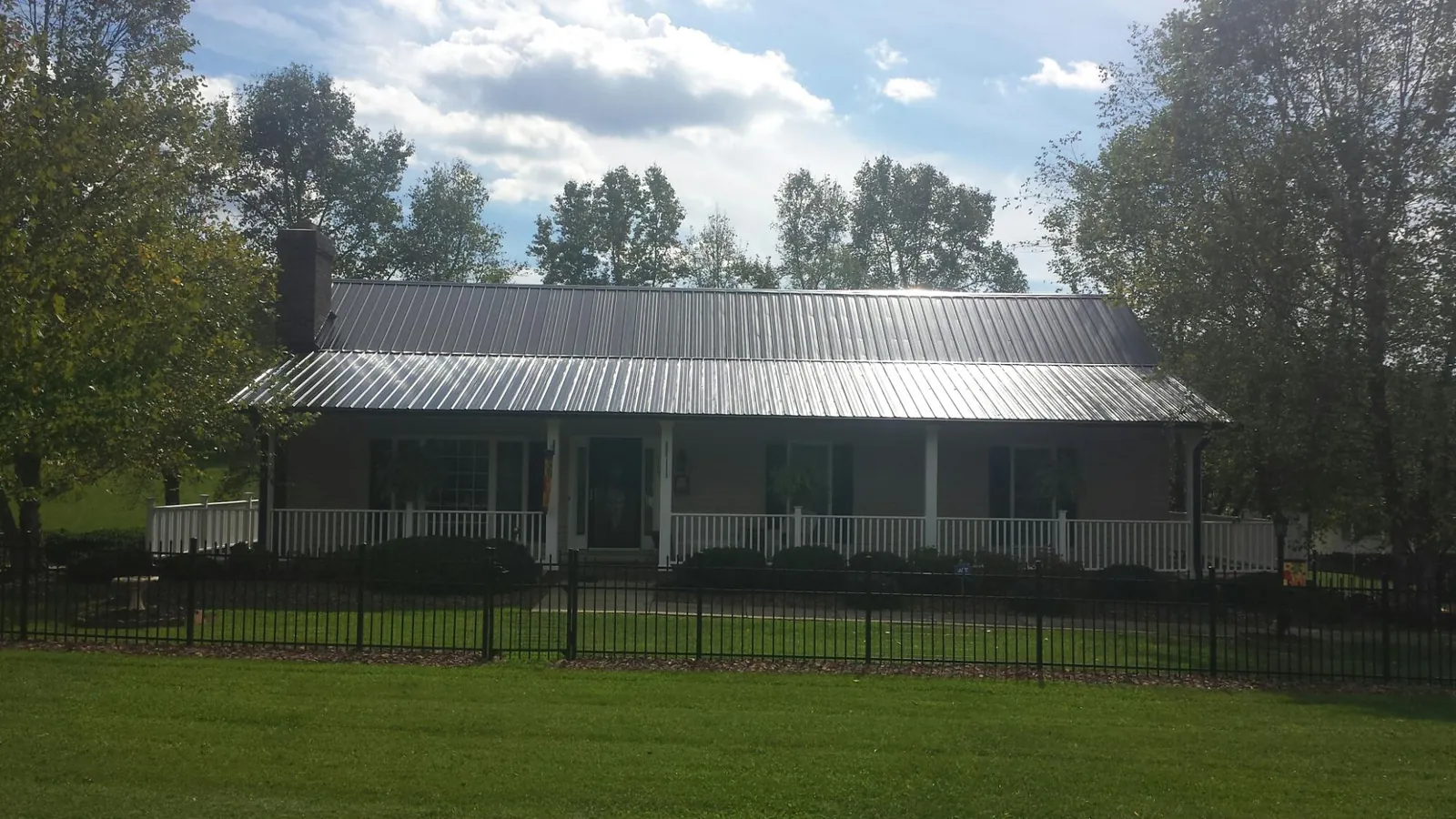 Gray metal roof on a brick ranch with a full width front porch — Gutter Guard Installation work by our crew in Hoquiam