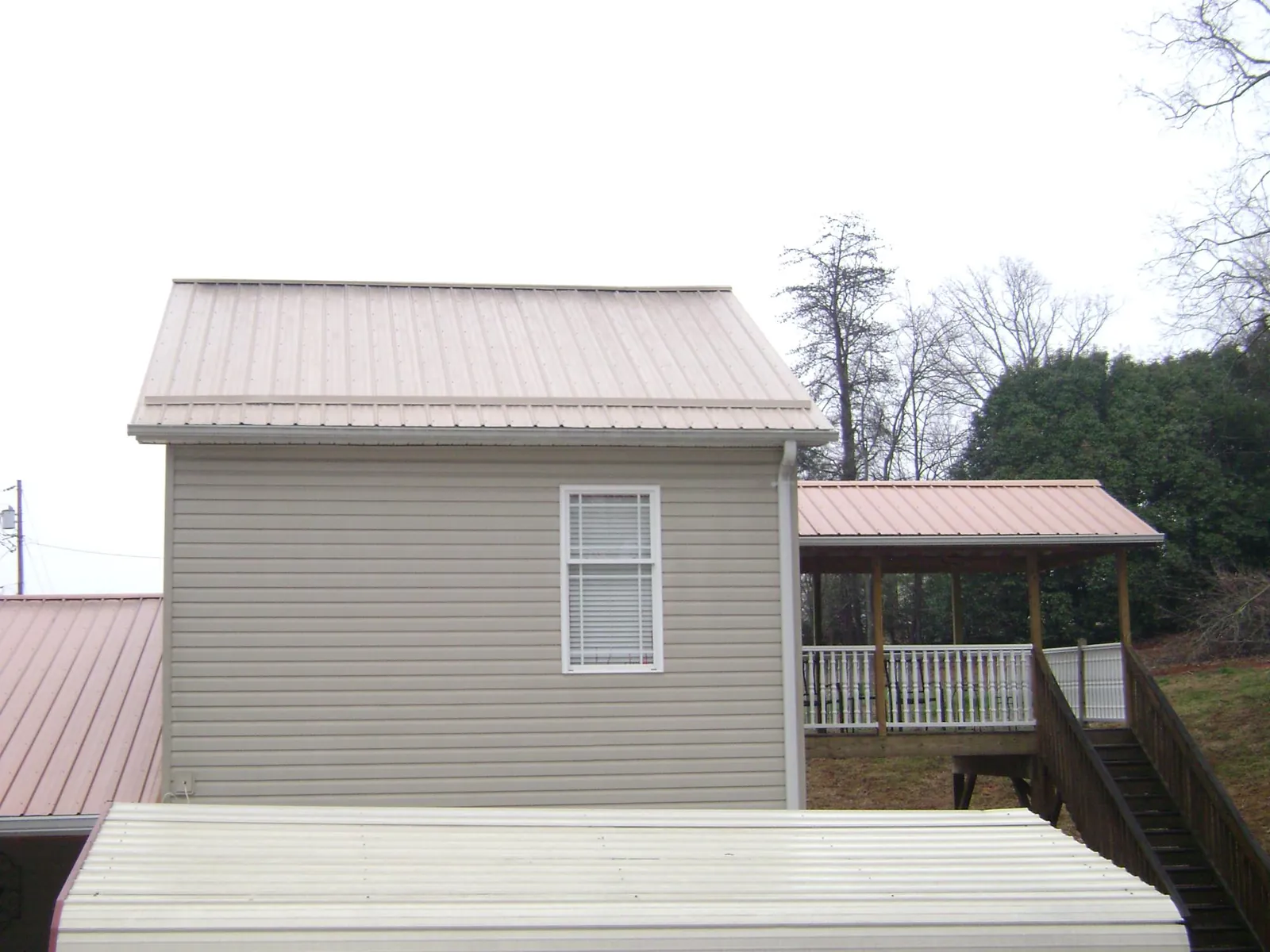 Tan metal roofs on a two story addition and attached porch, from a Roof Replacement job in Hoquiam