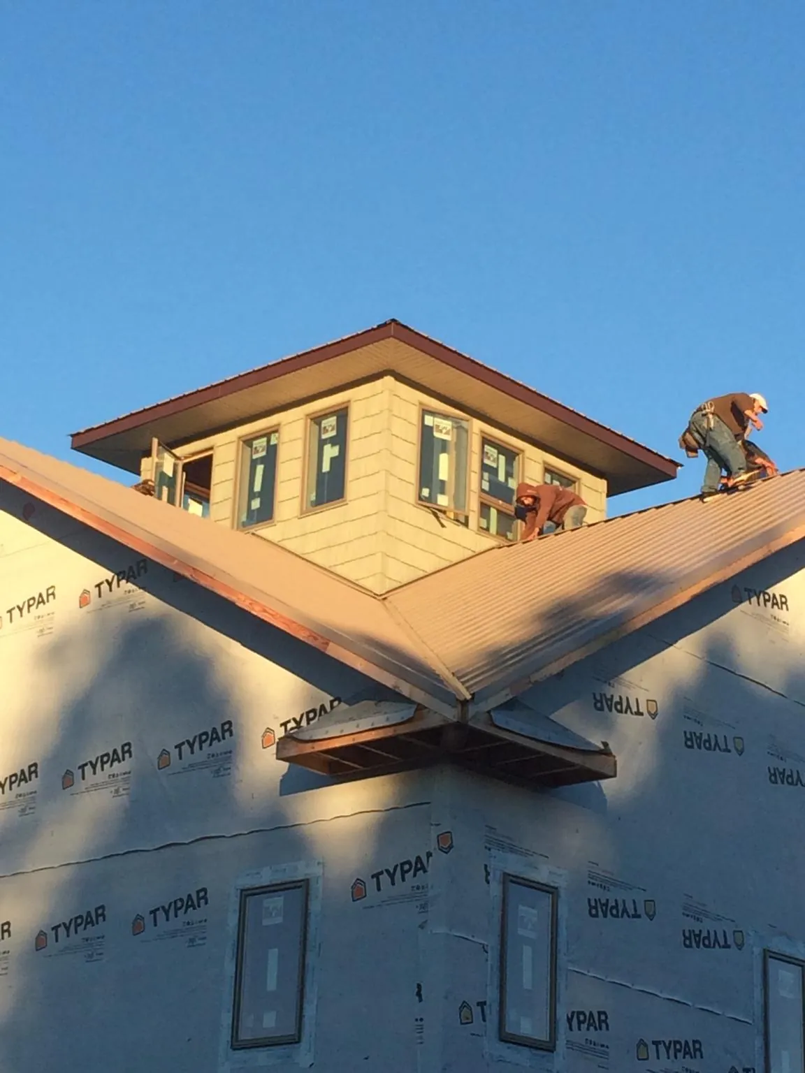 Roofers working around a rooftop cupola on a new metal roof at sunset — Roof Waterproofing in Hoquiam by Roofing Brothers